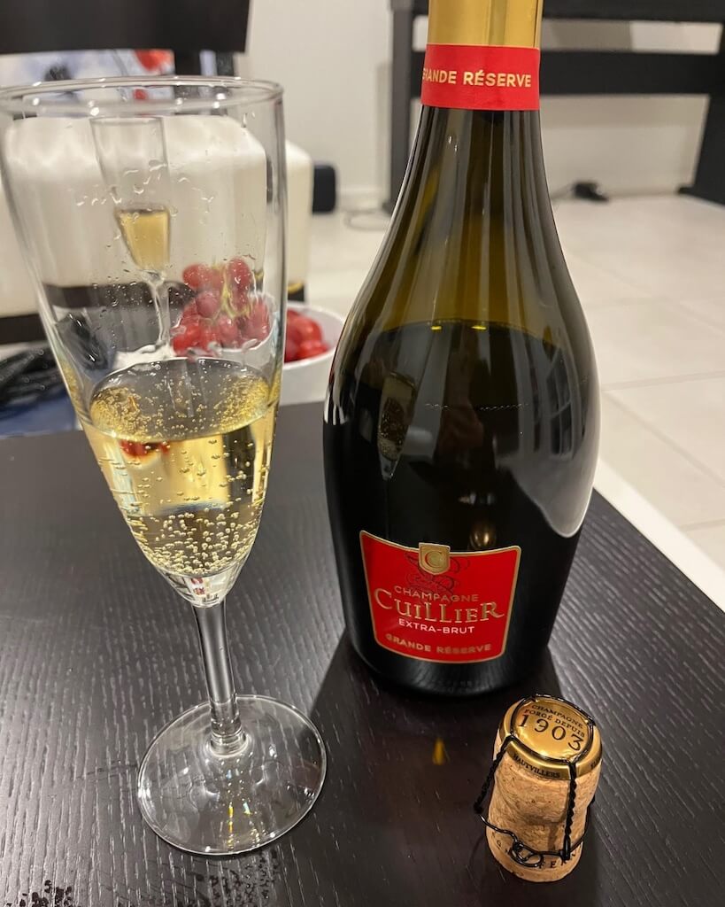 Bottle of Champagne Cuillier 'Cuvée Rouge' Grande Reserve with Champagne Flute showing off colour and bead of the Champagne